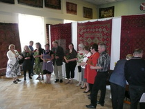 Iitin ryijyjen kirjo2012  -työryhmä kukitettavana näyttelyn avajaissa. Vas. Iitin ryijyjen kirjo -hankkeen idean äiti Sanna-Kaisa Spoof (FT) vierellään näyttelyn kuraattori Sirkka-Liisa Ranta (FT). Kolmas oikealta näyttelyn pystyttäjä Heimo Einola.